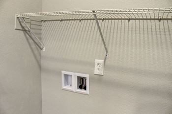 a wire closet organizer hangs on the wall next to two outlets at The Timbers Apartments, Evansville